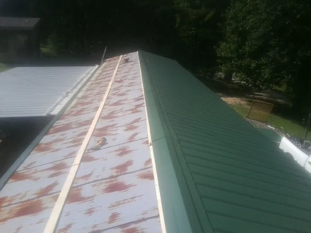 Old rusted panels beside newly installed green metal roofing — Wind Damage Roof Repair by Roofing Brothers in Gifford