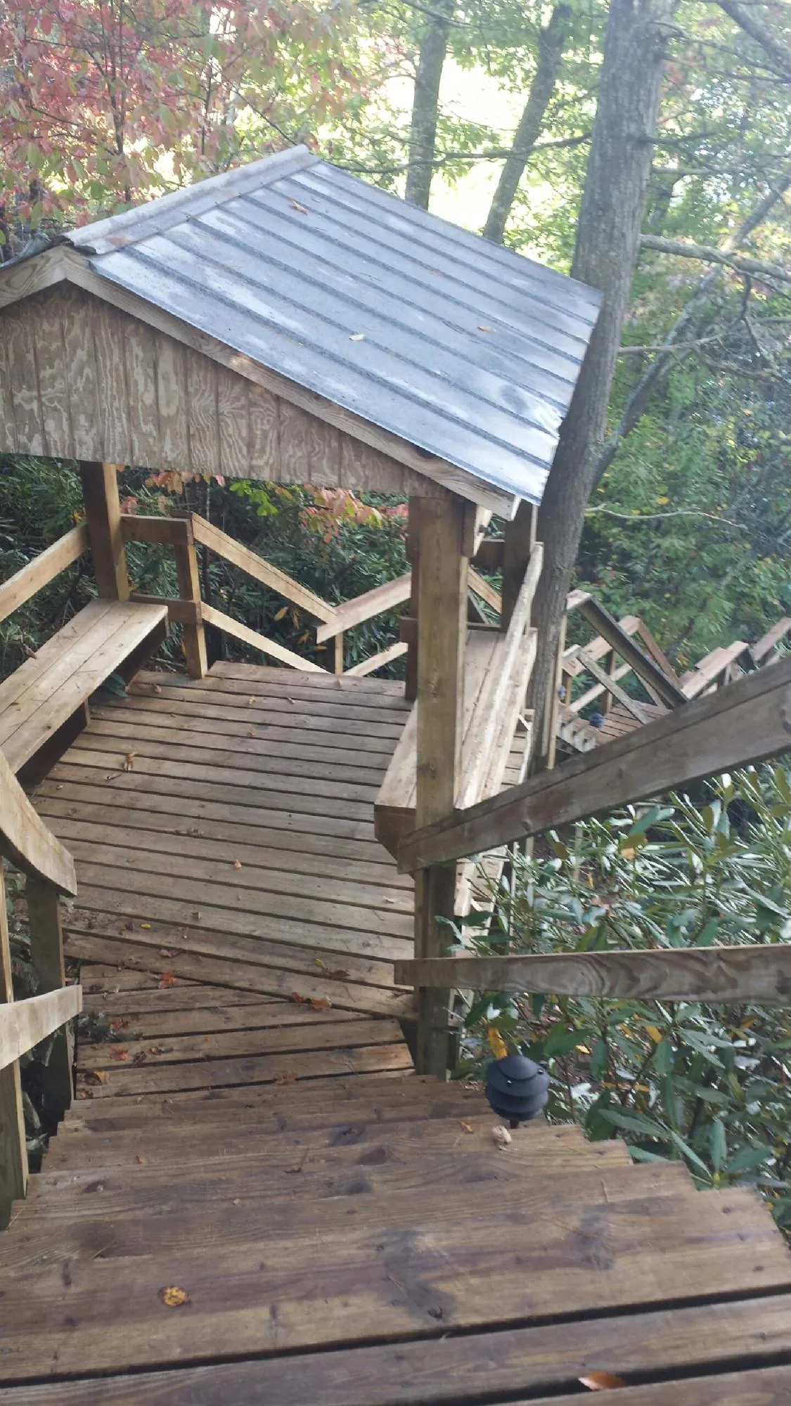 Metal roofed shelter over wooden steps on a wooded walkway — Skylight Repair & Installation work by our crew in Gifford