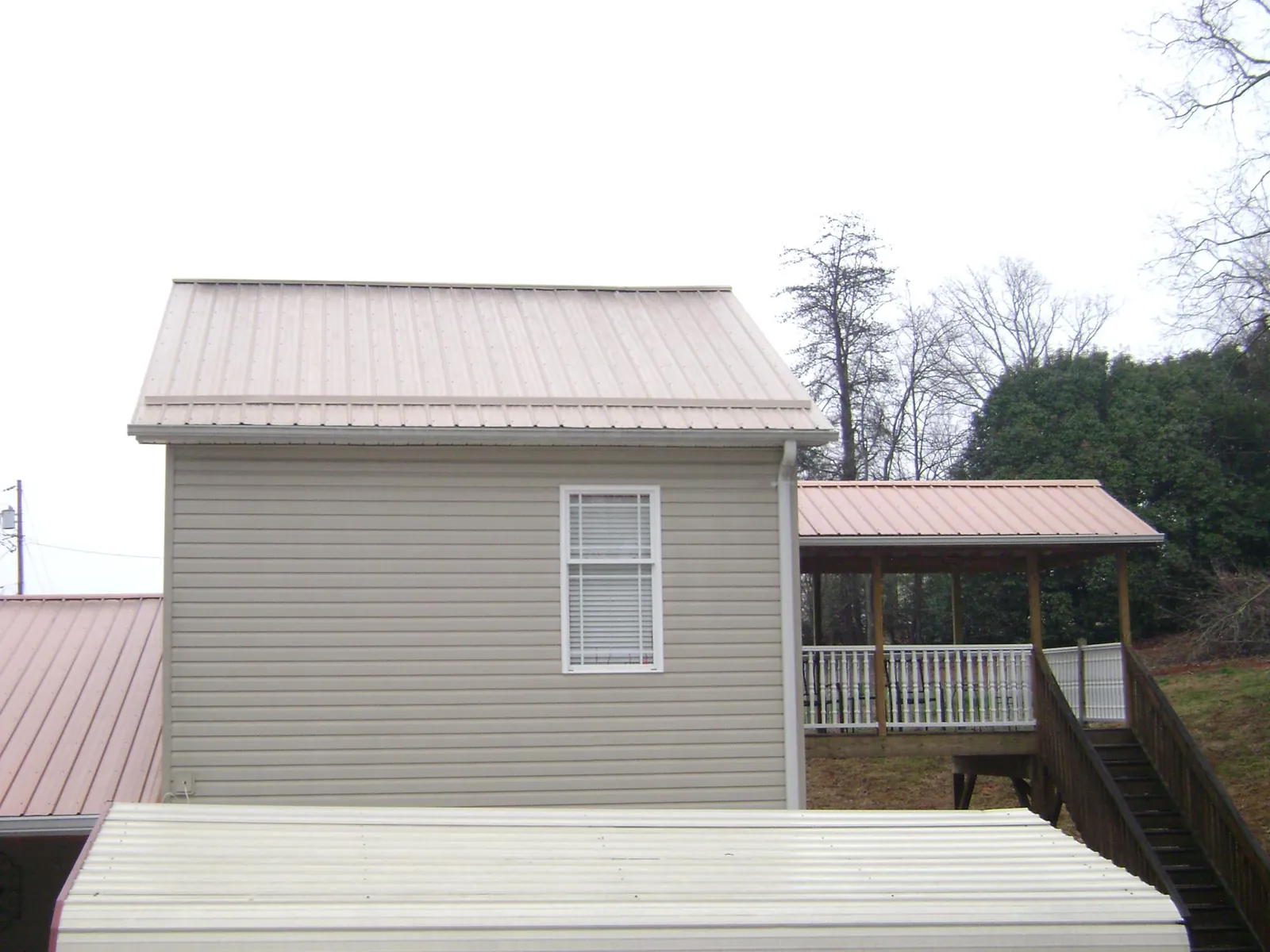 Tan metal roofs on a two story addition and attached porch, from a Roof Replacement job in Gifford