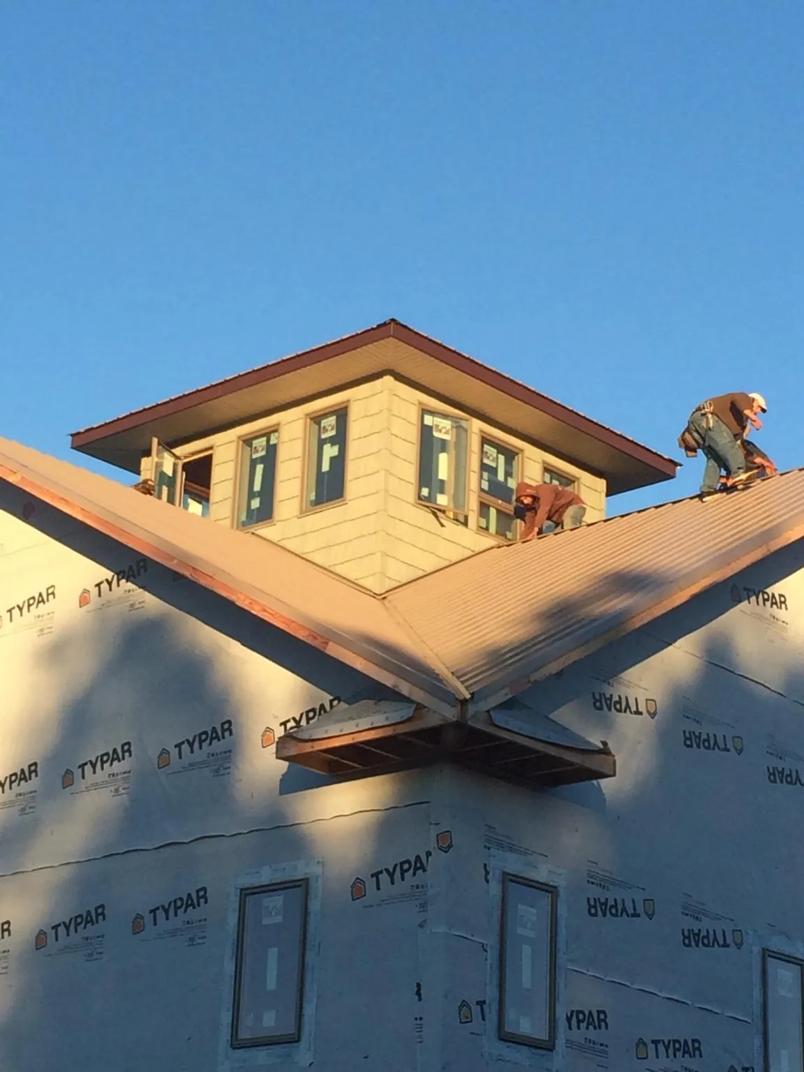 Roofers working around a rooftop cupola on a new metal roof at sunset — Roof Waterproofing in Gifford by Roofing Brothers